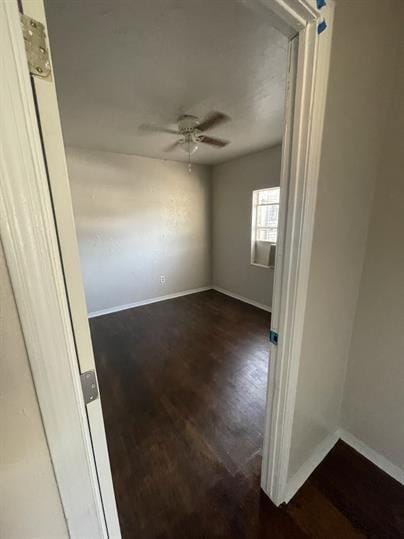 empty room featuring a ceiling fan, baseboards, and wood finished floors