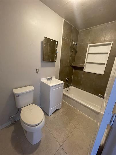 bathroom featuring toilet, tile patterned floors, washtub / shower combination, and vanity