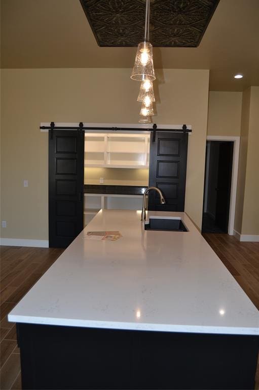 1124 NW 17 Th Pl, Newcastle, OK 73065 - kitchen with a barn door, a sink, light countertops, dark wood-type flooring, and a center island with sink
