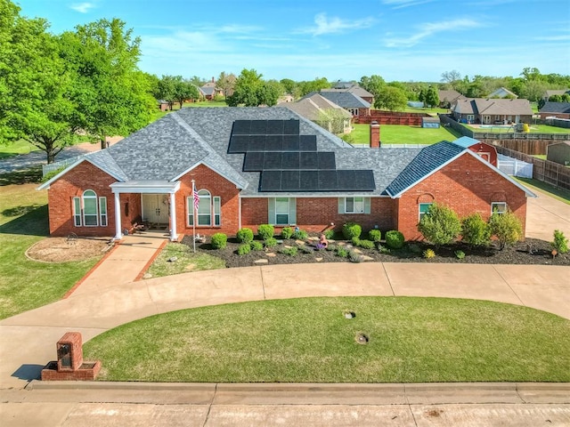 single story home with roof with shingles, brick siding, and solar panels