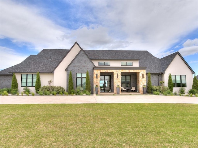view of front of home featuring a front lawn, stone siding, stucco siding, and a shingled roof