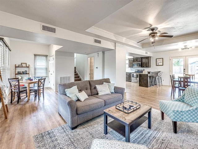 living area featuring visible vents, ceiling fan, and light wood-style floors