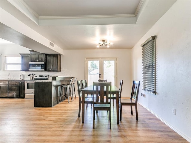 dining room featuring visible vents, light wood-style flooring, french doors, and a healthy amount of sunlight