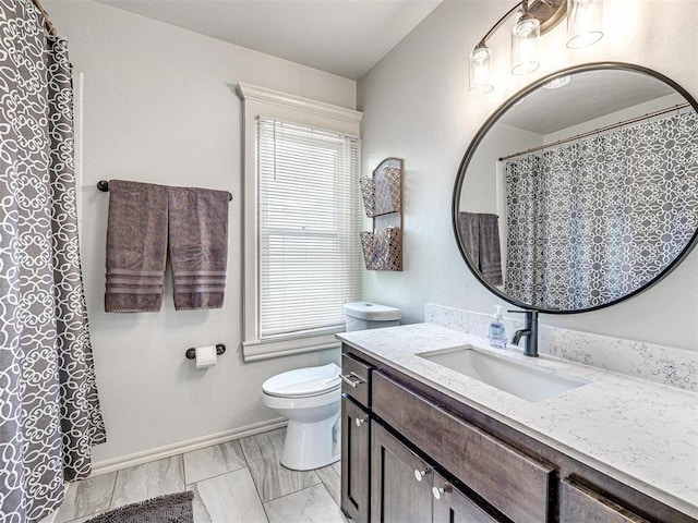 bathroom featuring toilet, marble finish floor, a wealth of natural light, and vanity