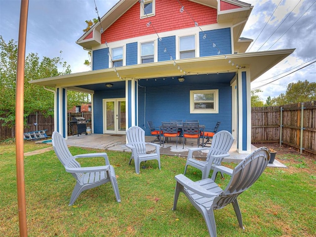 rear view of property featuring a lawn, french doors, and a fenced backyard