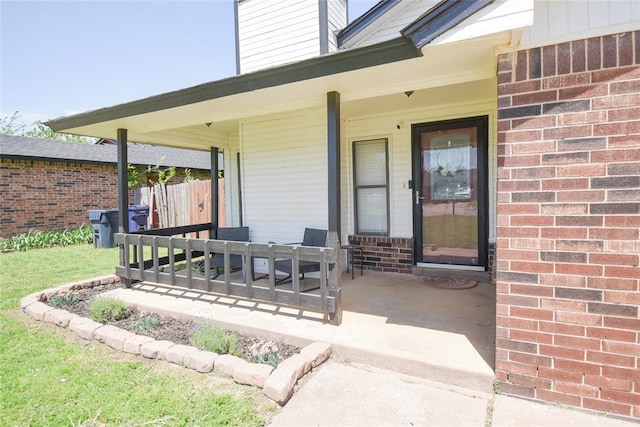 doorway to property featuring covered porch, a chimney, and brick siding