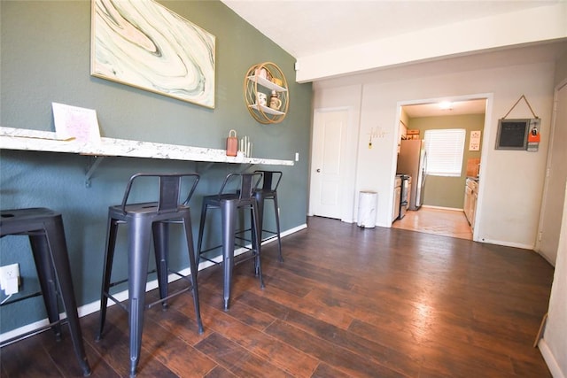 bar featuring freestanding refrigerator, wood finished floors, and baseboards