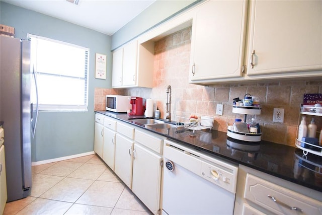 kitchen with dark countertops, white appliances, decorative backsplash, and a sink