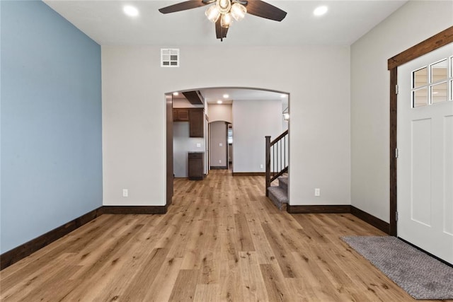 foyer entrance with arched walkways, visible vents, a ceiling fan, and baseboards