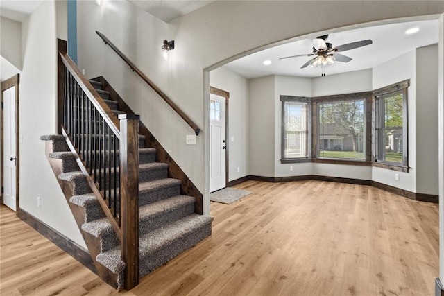 foyer entrance with wood finished floors, a ceiling fan, baseboards, and stairway