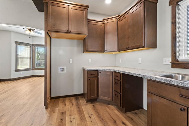 kitchen featuring a sink, baseboards, light wood-style floors, a ceiling fan, and light countertops