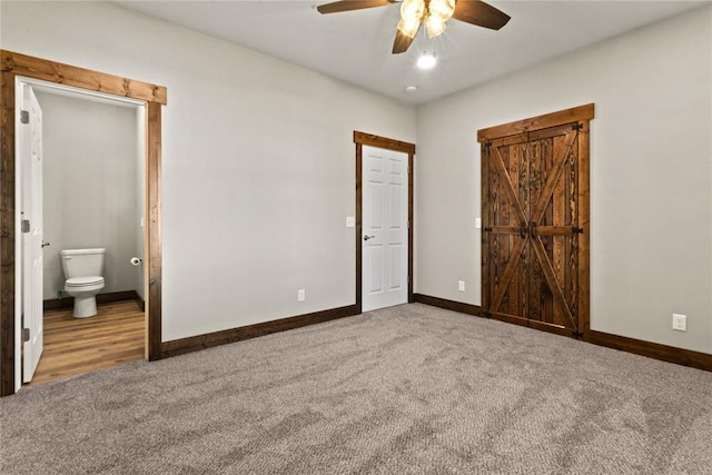 unfurnished bedroom with ensuite bath, carpet flooring, baseboards, and ceiling fan
