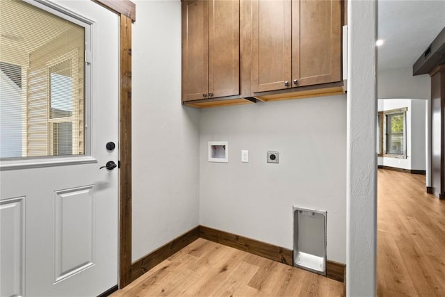washroom featuring hookup for a washing machine, electric dryer hookup, cabinet space, light wood-style flooring, and baseboards