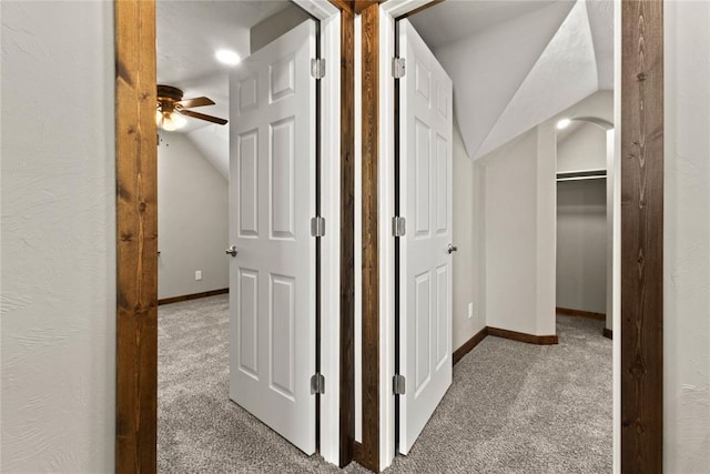 hall with baseboards, vaulted ceiling, and carpet flooring