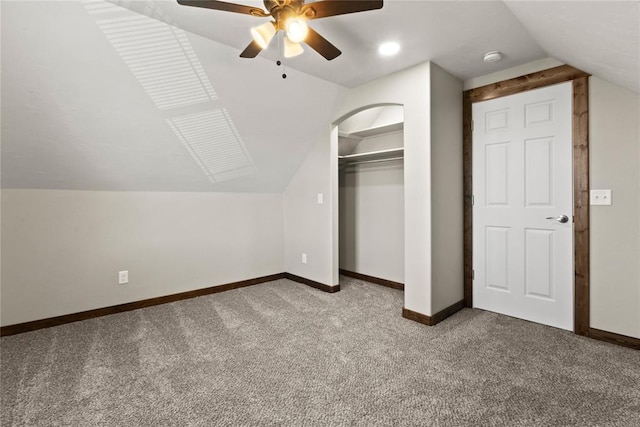 unfurnished bedroom featuring carpet flooring, baseboards, lofted ceiling, a ceiling fan, and a closet