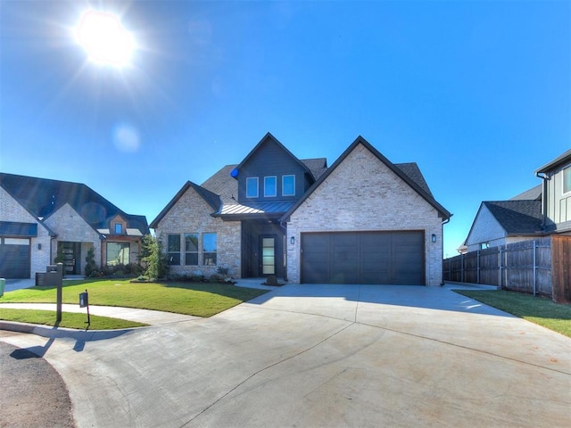 view of front of home featuring a standing seam roof, a front lawn, a garage, driveway, and fence