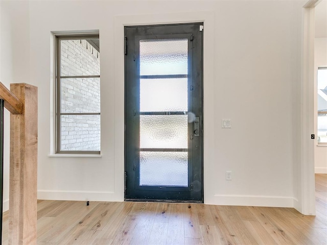 doorway to outside featuring baseboards and wood finished floors