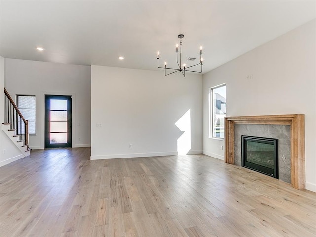 unfurnished living room featuring a wealth of natural light, light wood-style floors, and an inviting chandelier