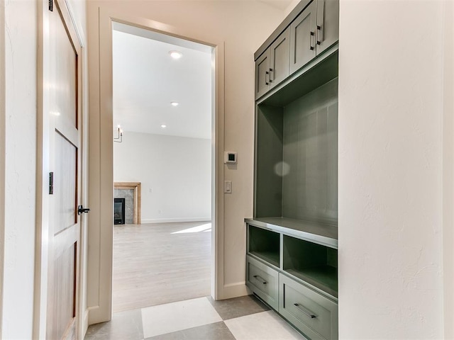 mudroom with light floors, baseboards, and a fireplace