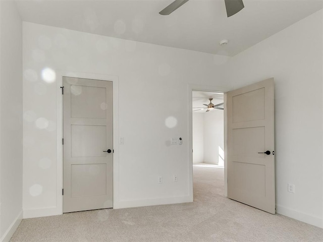 unfurnished bedroom with ceiling fan, light carpet, and baseboards
