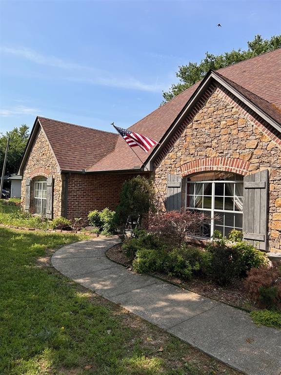 501 S 7th St, Okemah, OK 74859 - ranch-style house with stone siding, roof with shingles, and a front yard