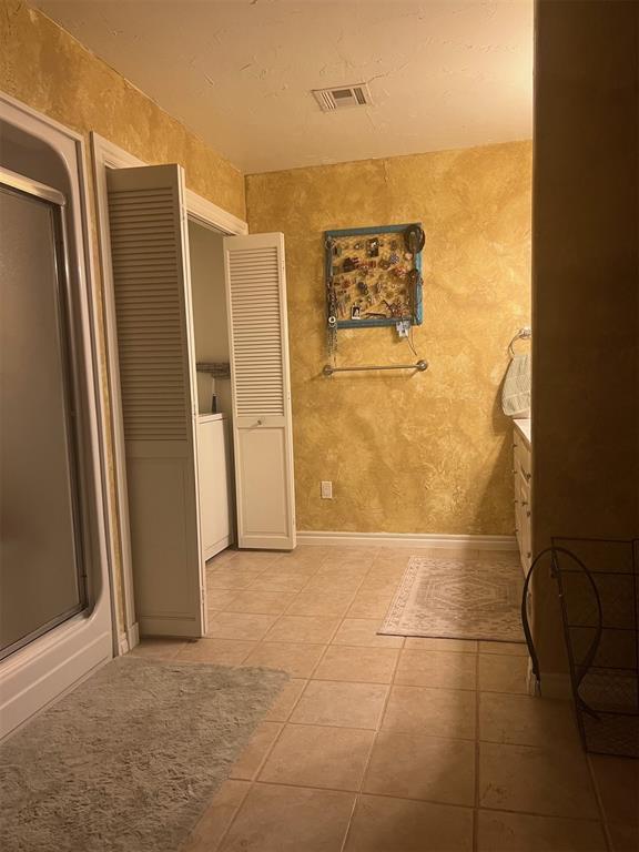 501 S 7th St, Okemah, OK 74859 - bathroom with tile patterned flooring, washer / dryer, a shower with door, and visible vents