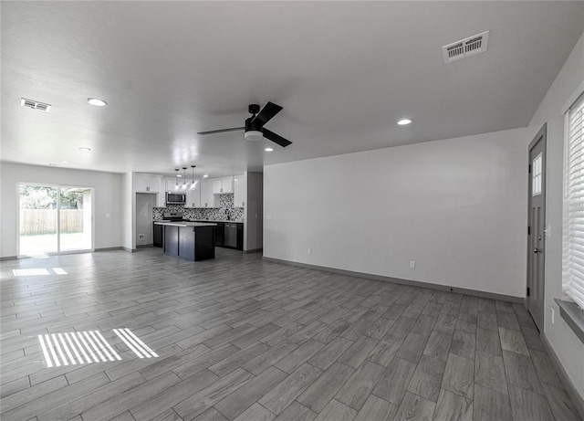 1717 Breckenridge Dr, Oklahoma City, OK 73115 - unfurnished living room featuring wood finished floors, visible vents, and ceiling fan with notable chandelier