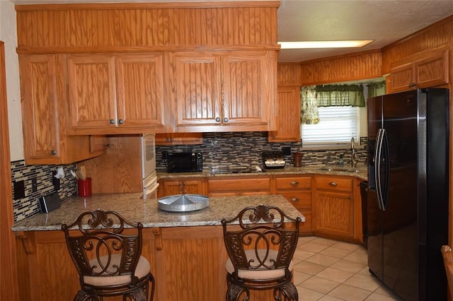 1400 S Indian Meridian Rd, Choctaw, OK 73020 - kitchen with light stone counters, tasteful backsplash, a sink, black appliances, and a peninsula
