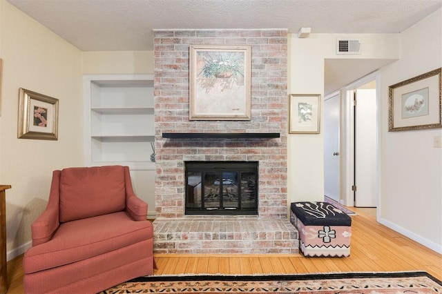 3200 W Britton Rd Unit 232, Oklahoma City, OK 73120 - living room featuring hardwood / wood-style floors, a fireplace, built in shelves, and a textured ceiling
