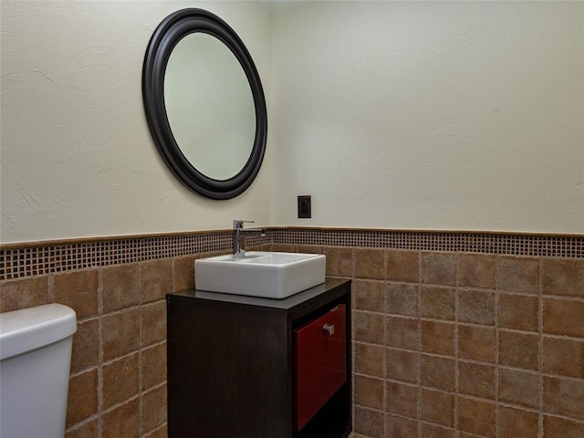 3025 Pine Ridge Rd, Oklahoma City, OK 73120 - half bath featuring tile walls, toilet, vanity, and wainscoting