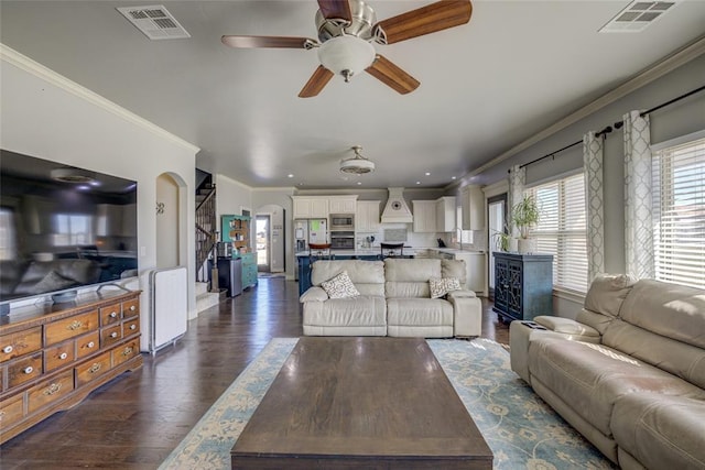 living area with ceiling fan, ornamental molding, dark wood-type flooring, and visible vents