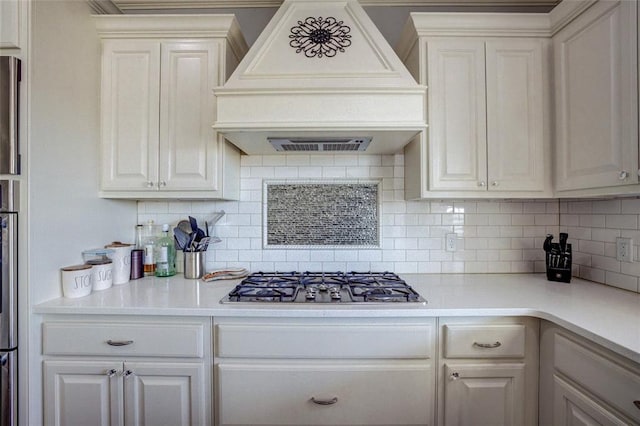 kitchen featuring light countertops, backsplash, stainless steel gas cooktop, and custom range hood