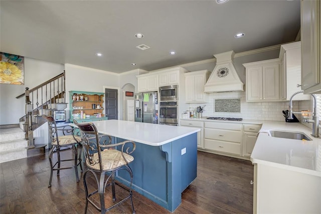 kitchen featuring stainless steel appliances, a sink, dark wood-style flooring, custom range hood, and a kitchen island