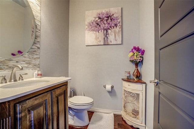 half bathroom featuring backsplash, toilet, vanity, and baseboards