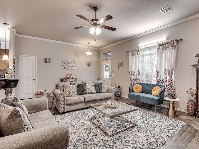 living area featuring ornamental molding, baseboards, visible vents, and ceiling fan