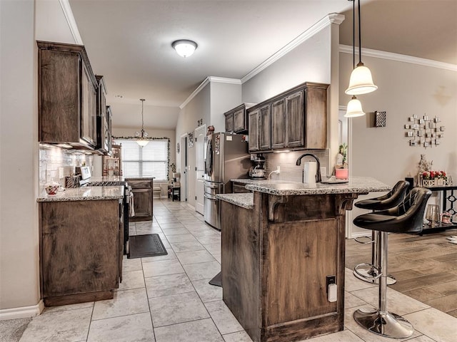 kitchen featuring a peninsula, backsplash, appliances with stainless steel finishes, and a kitchen breakfast bar