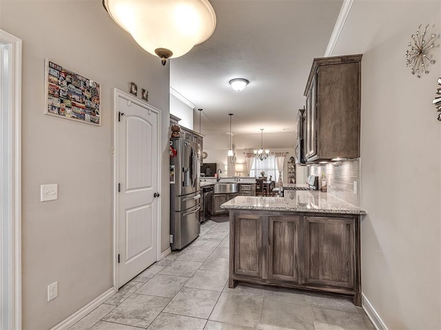 kitchen featuring a peninsula, a sink, dark brown cabinetry, light stone countertops, and stainless steel refrigerator with ice dispenser