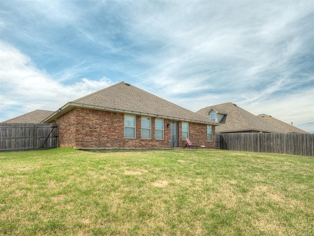 rear view of property with a fenced backyard, brick siding, and a lawn
