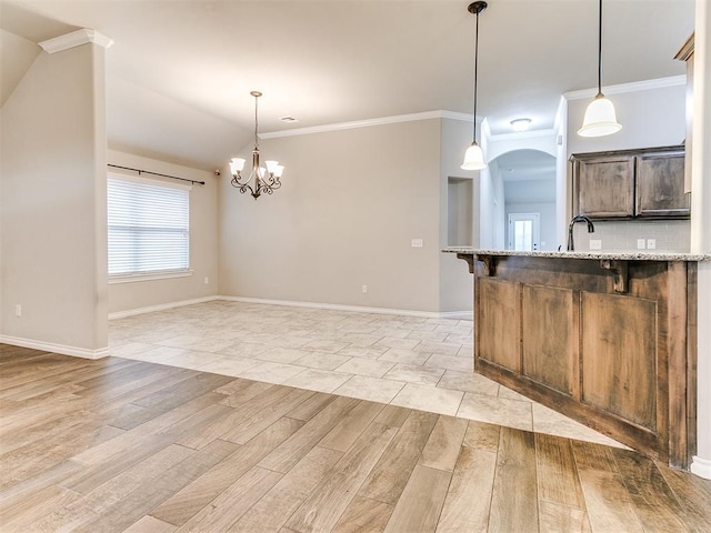 18232 Scarborough Dr, Edmond, OK 73012 - kitchen featuring light wood finished floors, a kitchen breakfast bar, ornamental molding, decorative light fixtures, and a chandelier