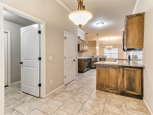18232 Scarborough Dr, Edmond, OK 73012 - kitchen featuring a peninsula, hanging light fixtures, ornamental molding, light stone counters, and a chandelier