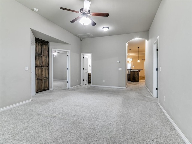 18232 Scarborough Dr, Edmond, OK 73012 - unfurnished bedroom featuring a walk in closet, connected bathroom, light carpet, and arched walkways