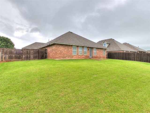 18232 Scarborough Dr, Edmond, OK 73012 - back of house with a fenced backyard, brick siding, and roof with shingles