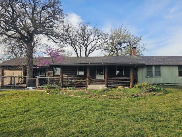 rear view of property featuring a yard, fence, a chimney, and a porch