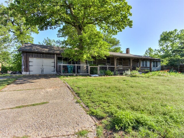 ranch-style home featuring a garage, a porch, a front yard, a chimney, and driveway