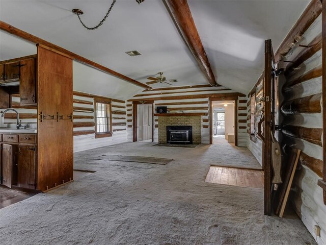 unfurnished living room with ceiling fan, visible vents, a fireplace, a sink, and lofted ceiling with beams