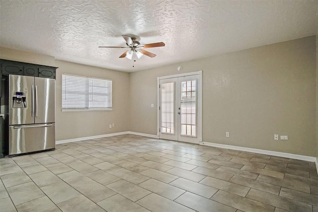 unfurnished room featuring baseboards, a textured ceiling, ceiling fan, and light tile patterned flooring