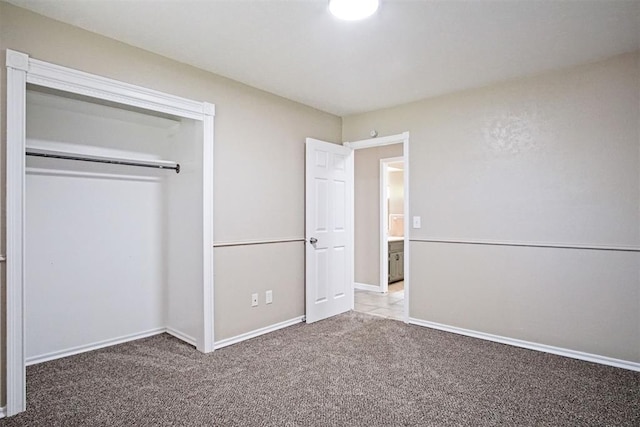 unfurnished bedroom featuring baseboards, carpet floors, and a closet
