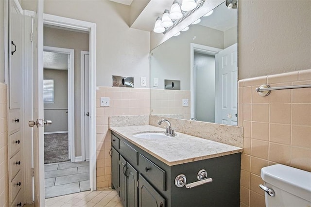 bathroom with tile walls, tile patterned flooring, vanity, and toilet