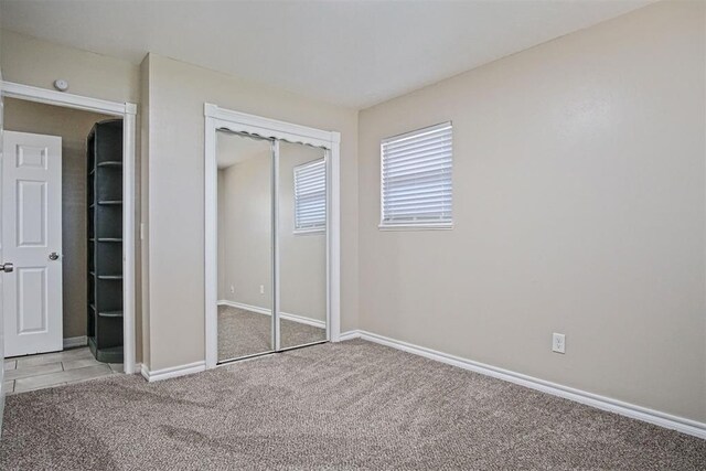 unfurnished bedroom featuring baseboards, carpet flooring, and a closet