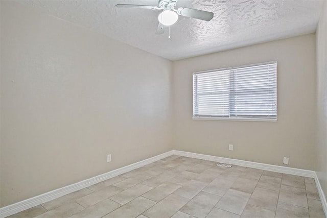 unfurnished room with light tile patterned flooring, a textured ceiling, a ceiling fan, and baseboards